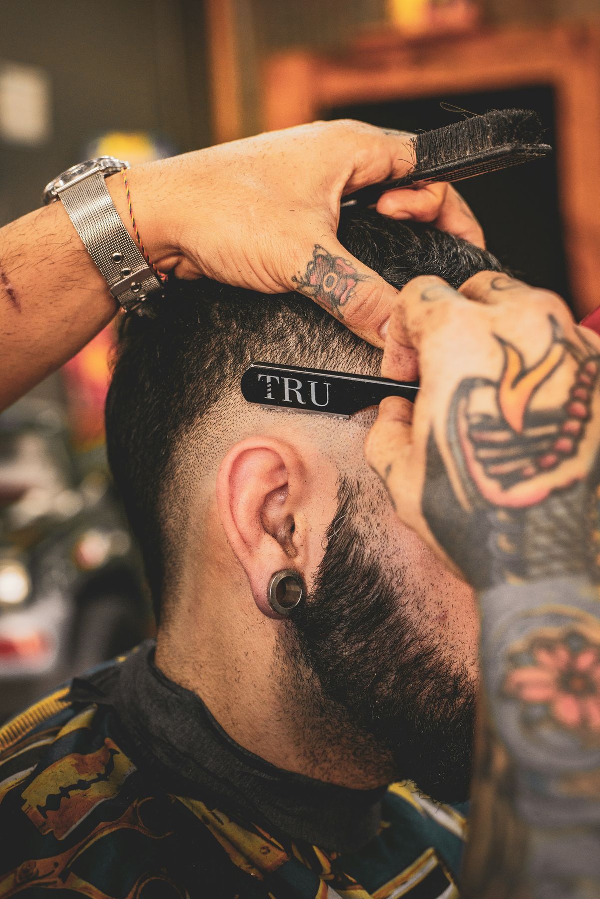 A barber shaping a client's fade