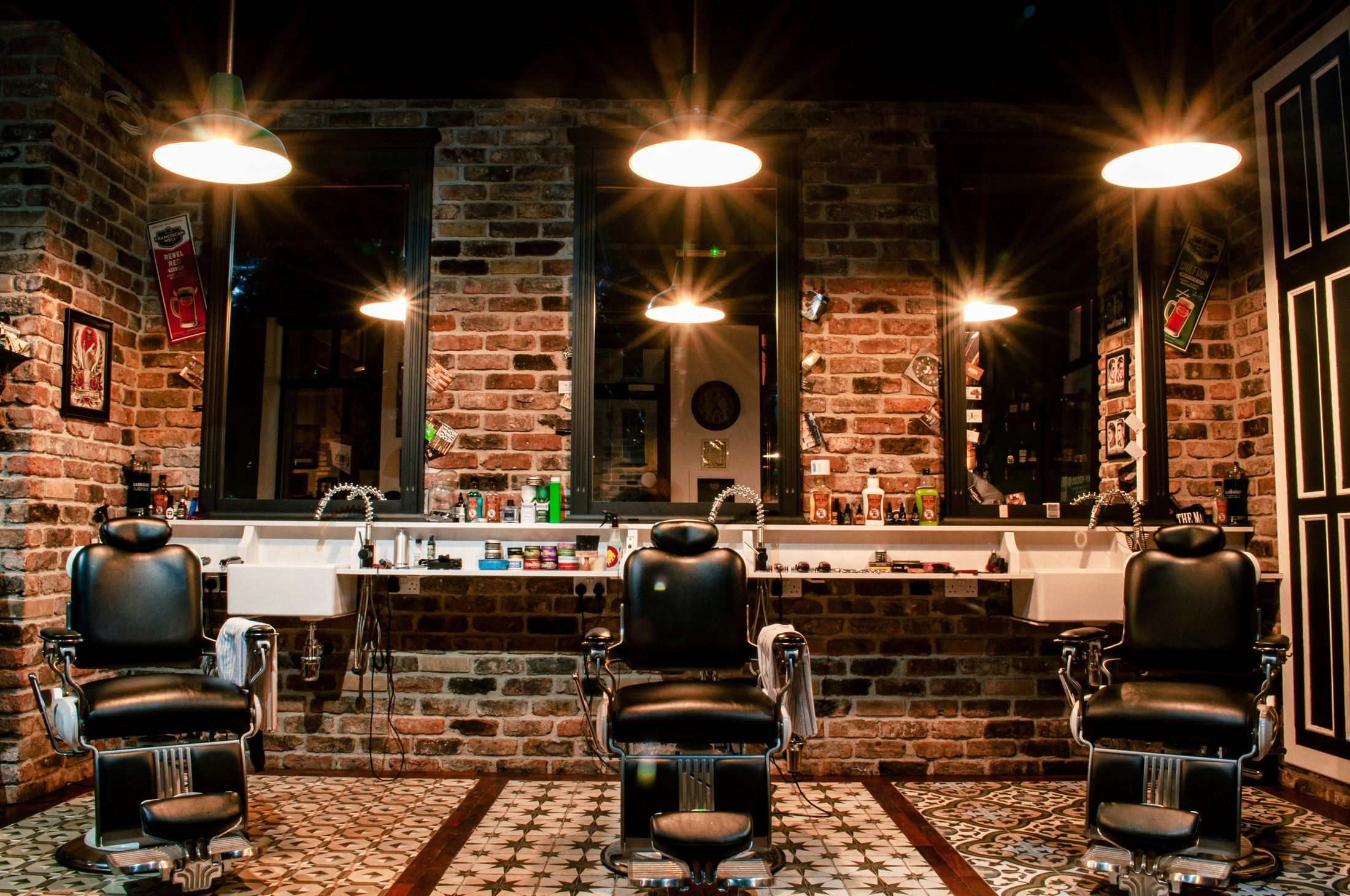A barbershop with leather barber chairs and a brick wall