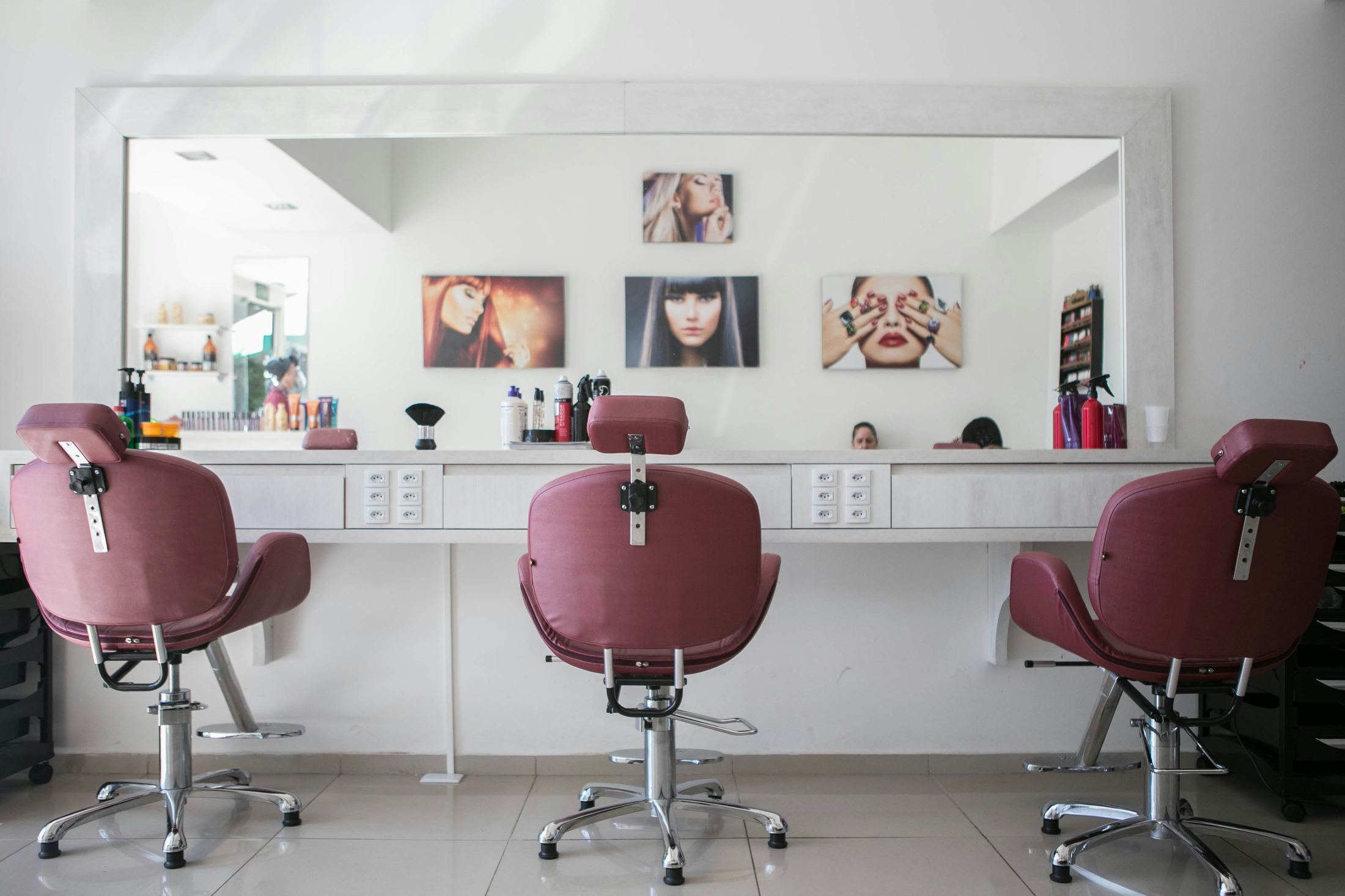 A beauty salon with rose-coloured treatment chairs and a long mirror