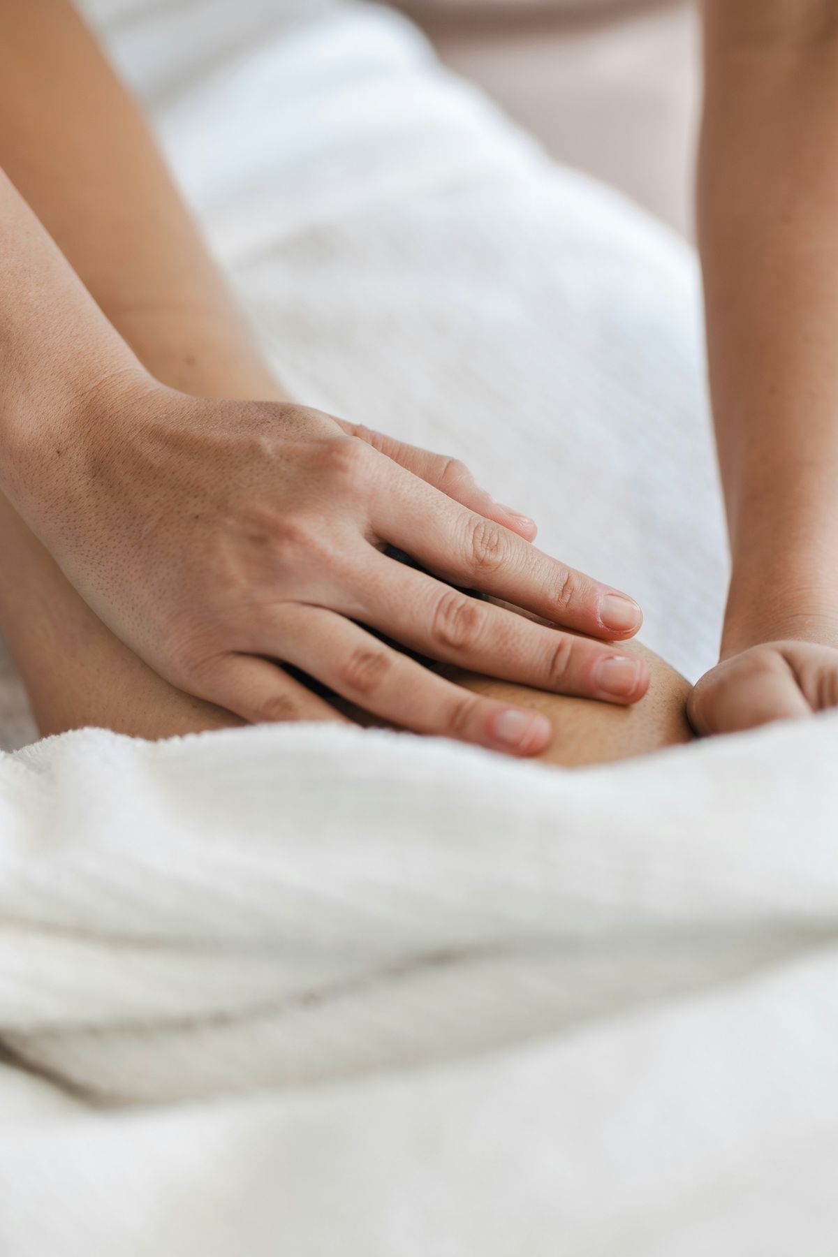 A therapist's hands working over a white towel