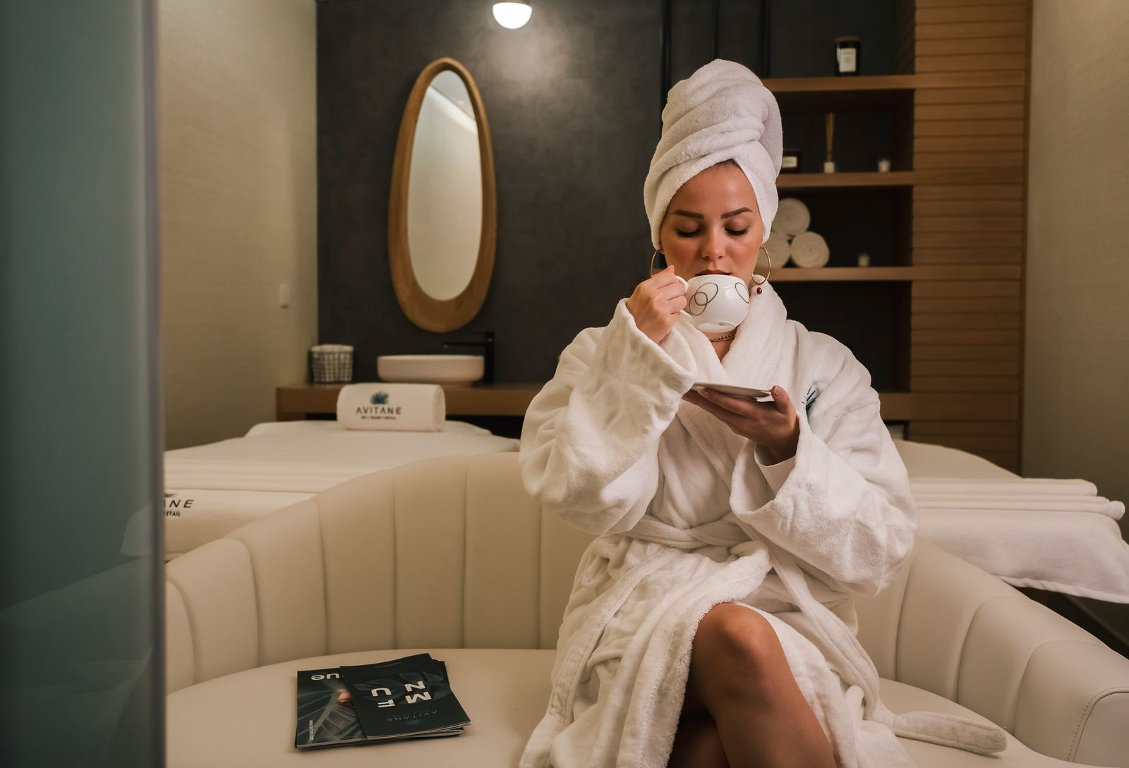 A client in a robe relaxing with tea in a spa lounge